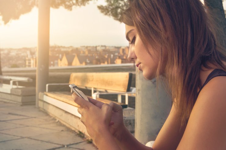 ragazza seduta con il cellulare in mano