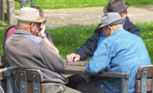 quattro anziani seduti attorno ad un tavolo che giocano a carte