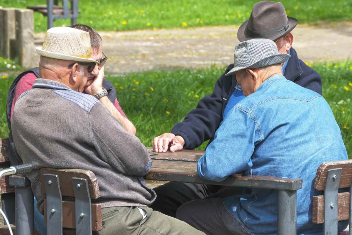 quattro anziani seduti attorno ad un tavolo che giocano a carte