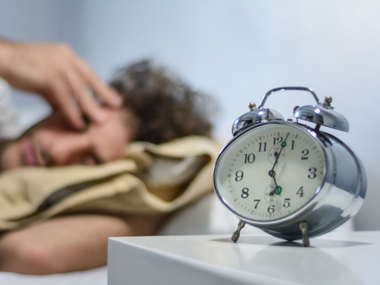 uomo che dorme con sveglia sul comodino
