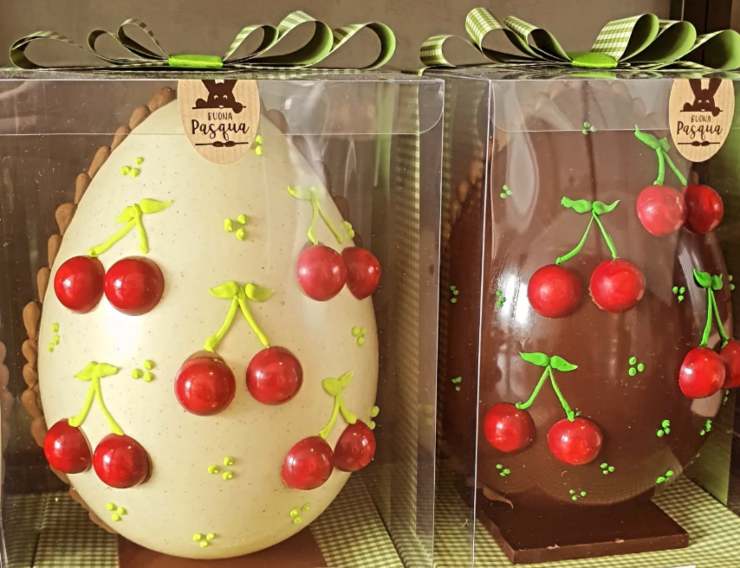 due uova di cioccolato decorate dentro confezioni trasparenti